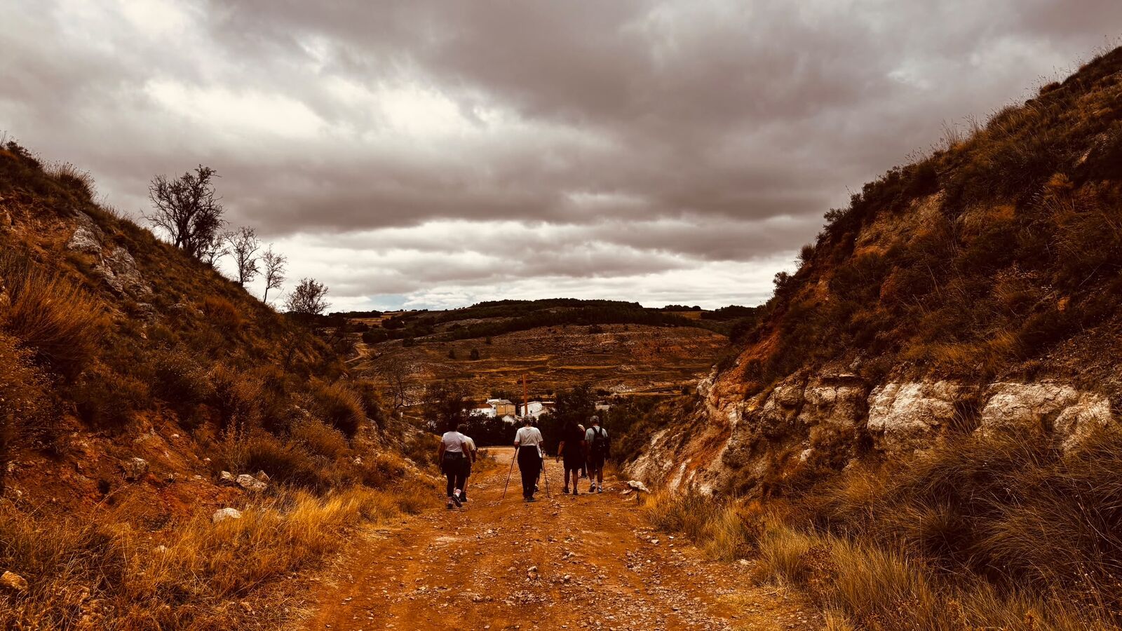 Peregrinos atravesando un barranco bajo un cielo nublado
